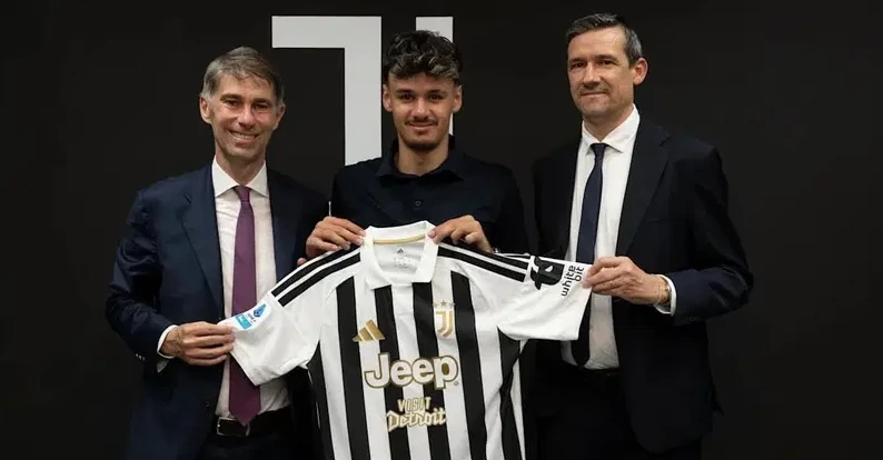 Fudbaler drži dres Juventusa sa dvojicom zvaničnika