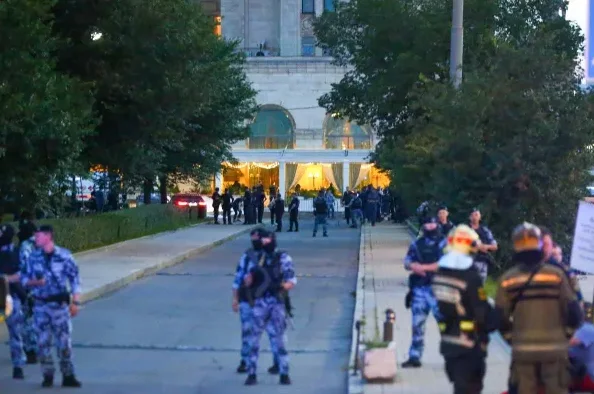 Grupa policajaca u uniformama i vatrogasaca sa opremom nalazi se ispred velike zgrade.