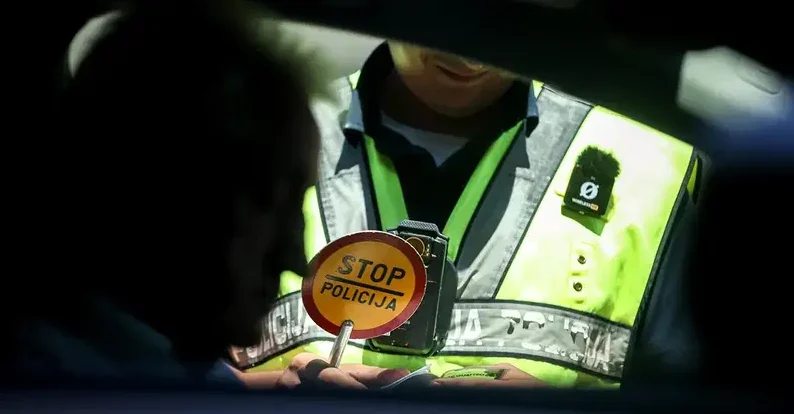 Policajac saobraćajne policije drži ručni znak "STOP POLICIJA" i policijski radar za mjerenje brzine.