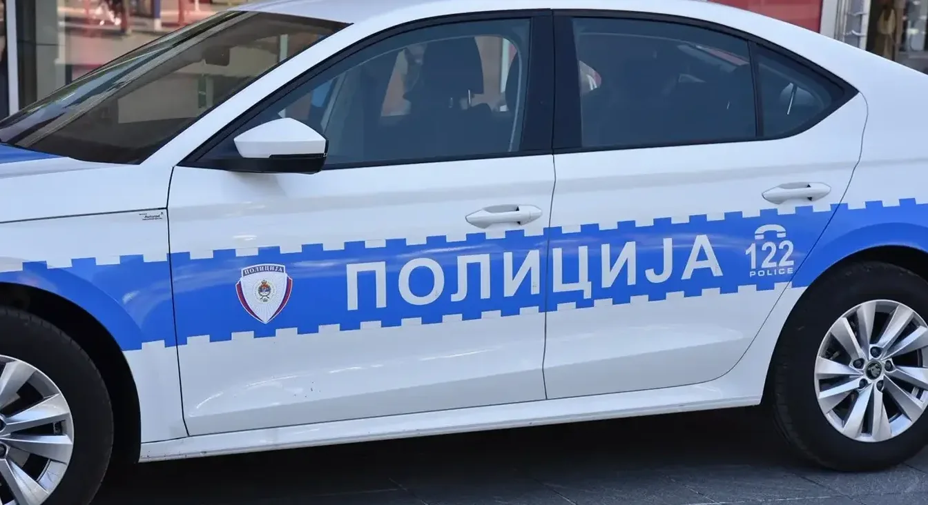 Bijelo policijsko vozilo sa plavom trakom i natpisom "POLICIJA"