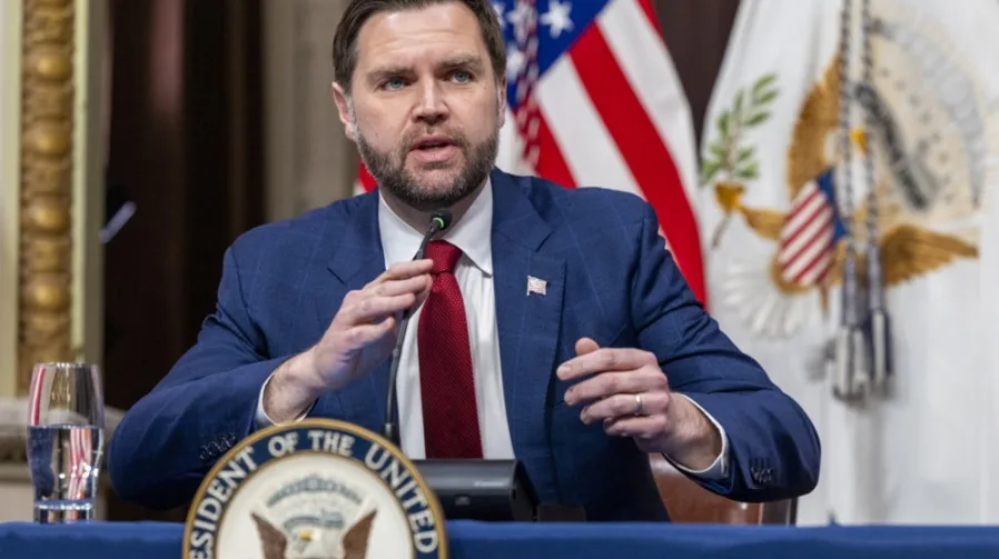 Američki predsjednik Dž.D. Vens nosi tamnoplavo odijelo i crvenu kravatu, držeći govor za govornicom.