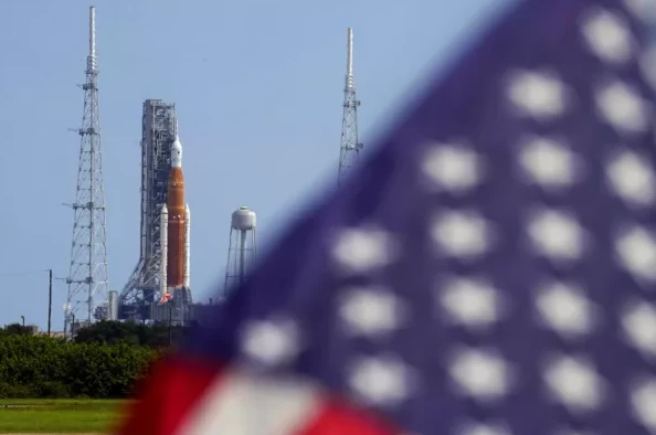 Raketa Artemis na lansirnoj rampi sa američkom zastavom koja se nazire u prvom planu.