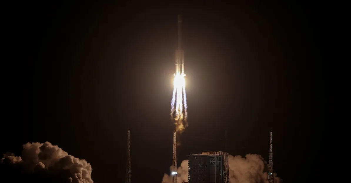 Raketa se diže u noćno nebo sa jarkim plamenom i ispušnim gasovima.