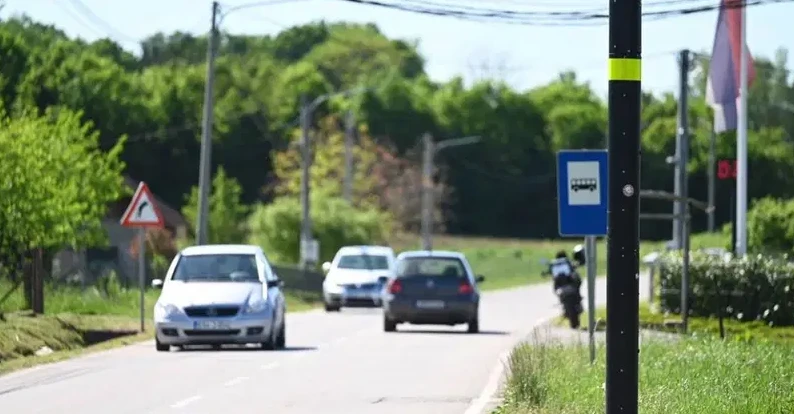 Saobraćaj na putu sa autobuskom stanicom i saobraćajnim znakom