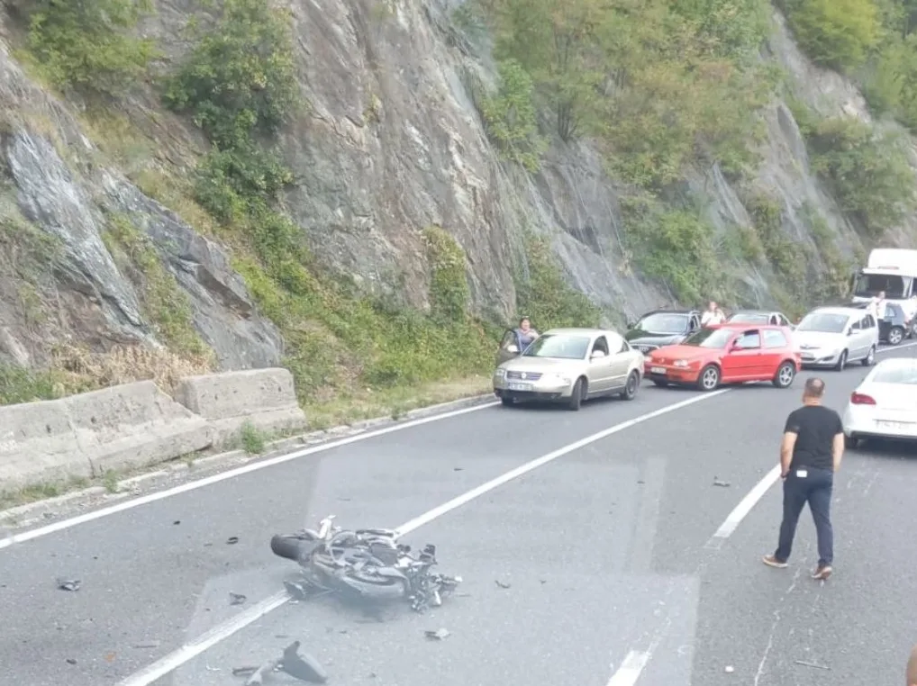 Saobraćajna nesreća sa prevrnutim motorom na putu, okružen sa nekoliko automobila i kamionom, na stjenovitoj padini pored puta.