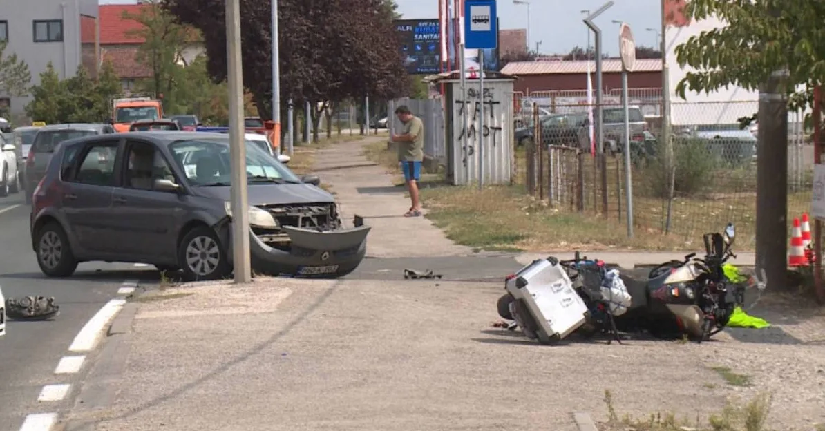 Automobilska nesreća sa motociklom pored puta, oštećeni automobil i prevrnuti motocikl.