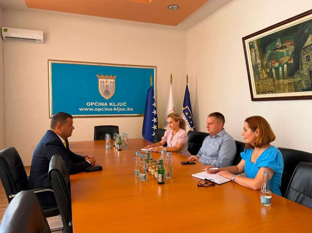 Sastanak u Općini Ključ: Na fotografiji se vide načelnik Općine Ključ sa saradnicima, kao i predstavnici partnerske institucije, kako sjede za velikim okruglim stolom.