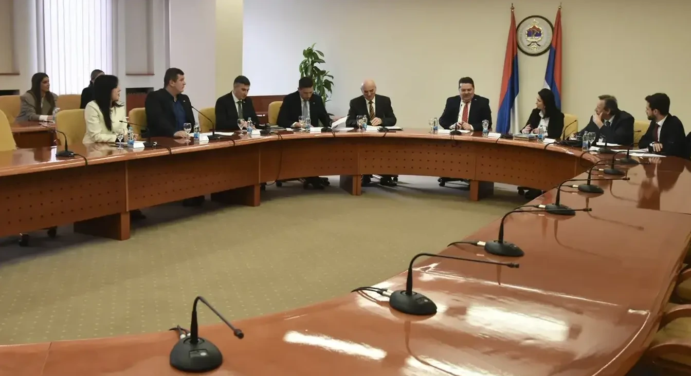 Grupa ljudi sjedi za velikim ovalnim stolom u sali za konferencije.
