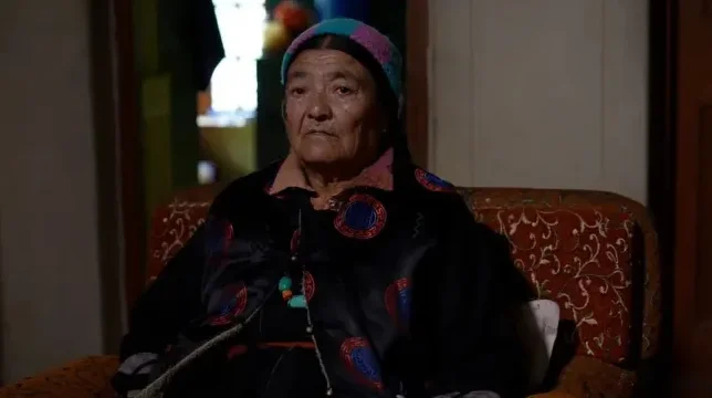 Portret starije žene u tradicionalnoj nošnji, sjedi na stolici