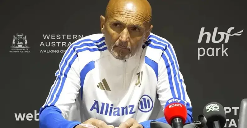 stariji muškarac sa ćelavom glavom, sjedi i nosi bijelu majicu sa plavim prugama i logotipima "Adidas" i "Allianz"