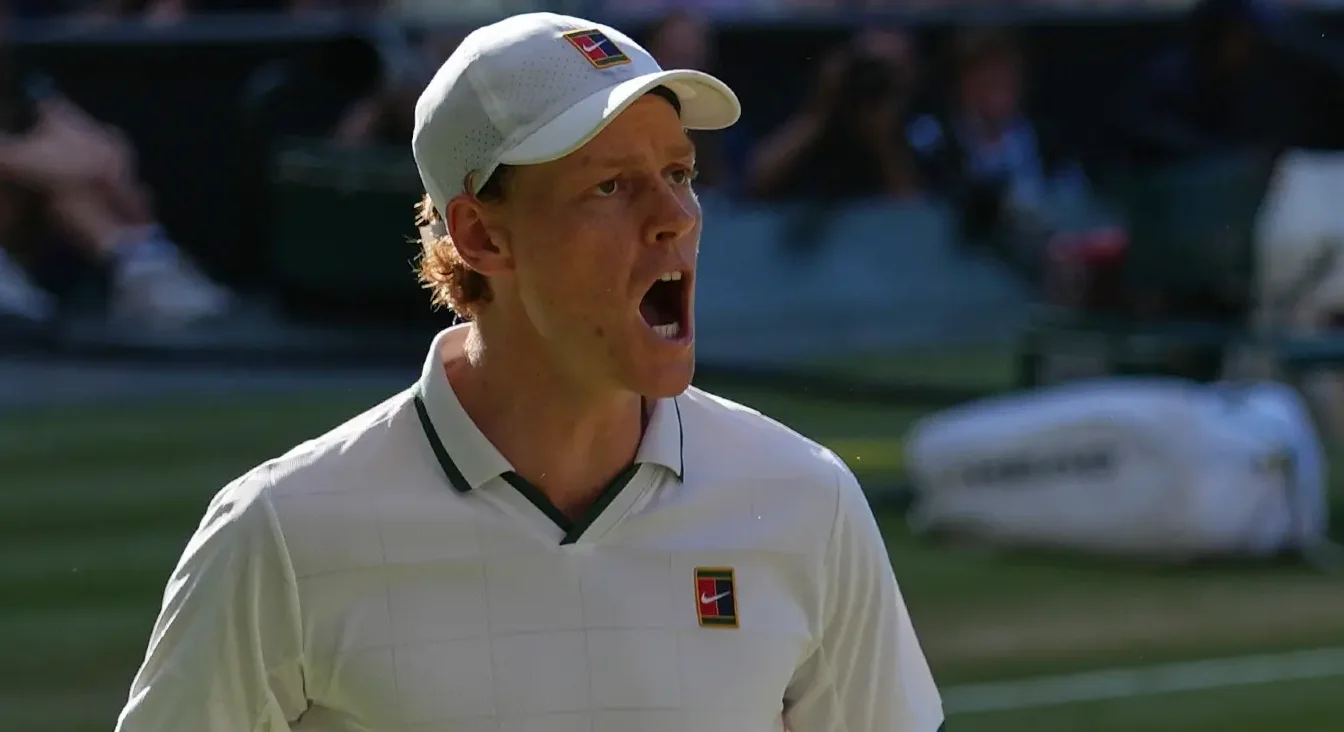 Teniser sa otvorenim ustima, noseći bijelu kapu i majicu, na teniskoj utakmici na Wimbledonu.