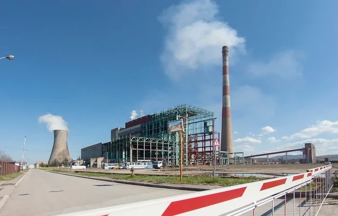 Termoelektrana sa rashladnim tornjem i visokim dimnjakom, sa dimom koji izlazi iz oba.