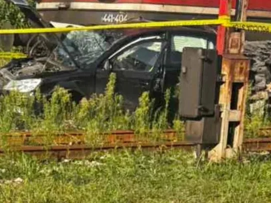 Crni automobil teško oštećen nakon sudara s vozom na željezničkoj pruzi.
