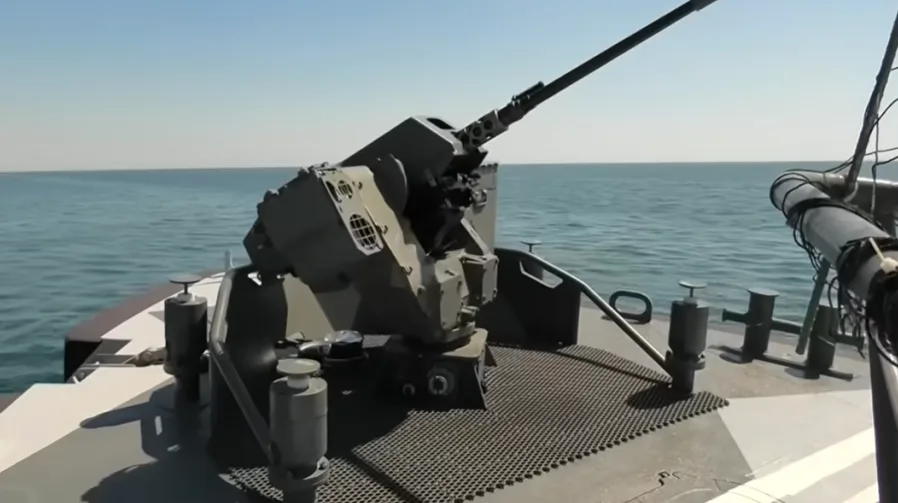 Automatski top montiran na palubi vojnog broda, s pogledom na more i nebo.