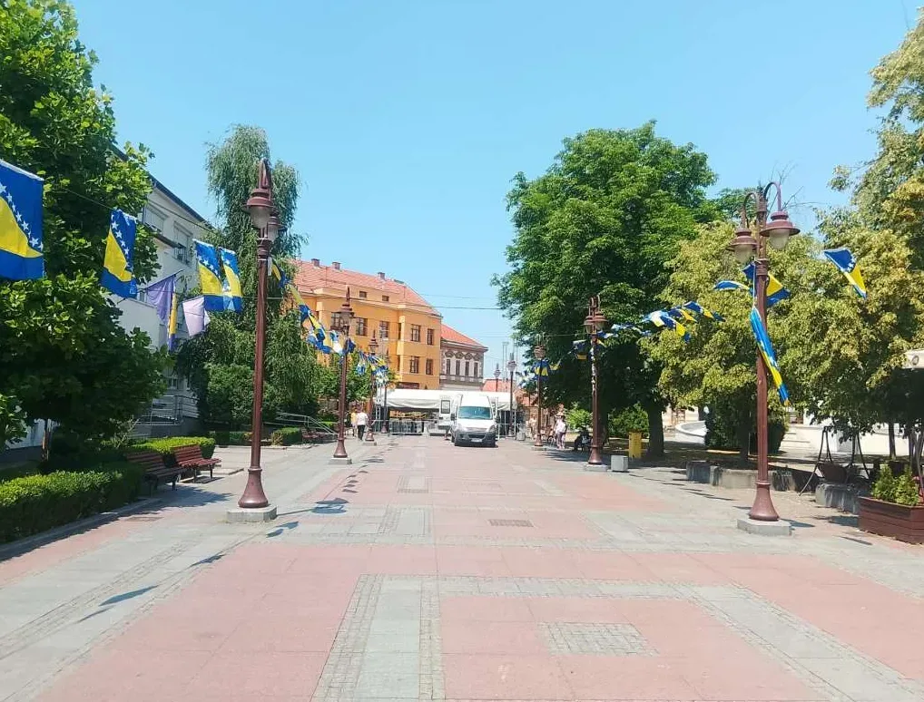 Uređen trg sa drvoredom i zastavama Bosne i Hercegovine.