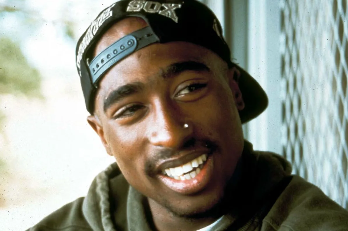 Tupac Shakur nosi crnu kapu s natpisom 'SOX'.