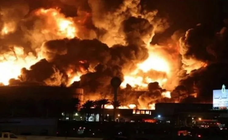 Veliki požar sa gustim dimom i plamenom iznad industrijske zgrade noću.