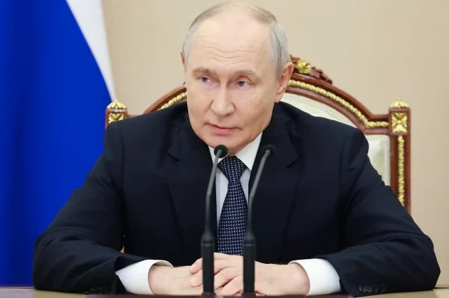 Vladimir Putin sjedi za stolom sa dva mikrofona ispred sebe, u tamnom odijelu i bijeloj košulji sa plavo-bijelom kravatom.
