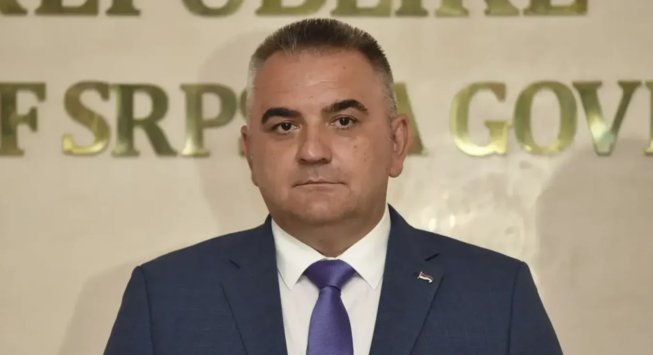 Portret muškarca u tamnoplavom odijelu i sa ljubičastom kravatom.