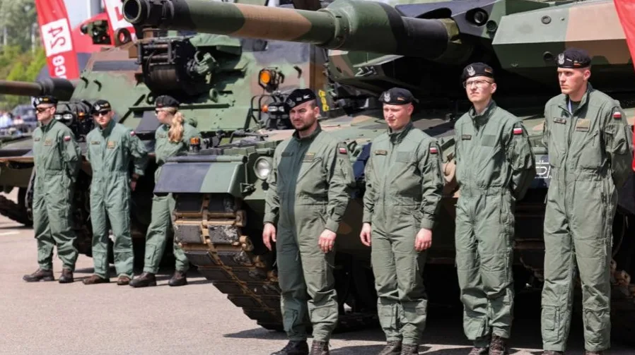 Pripadnici poljske vojske u uniformama stoje pored tenka.