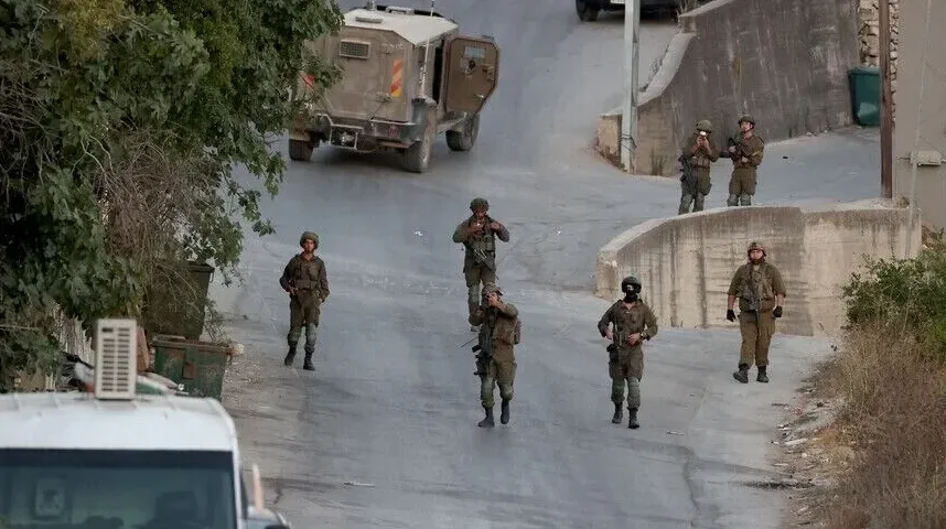 Pripadnici vojske u uniformama i sa oružjem patroliraju ulicom.