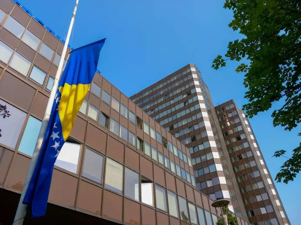 Zastava Bosne i Hercegovine na pola koplja ispred moderne zgrade