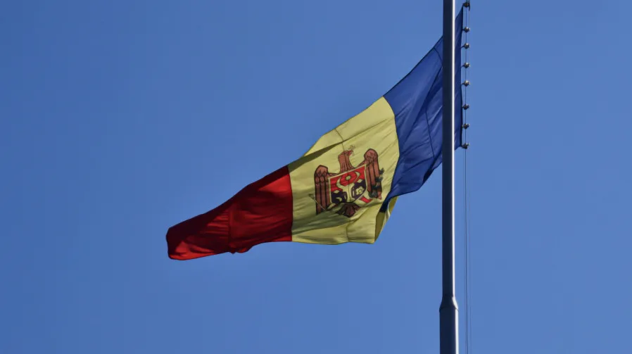 Moldavska zastava vijori se na jarbolu na pozadini jasnog plavog neba.