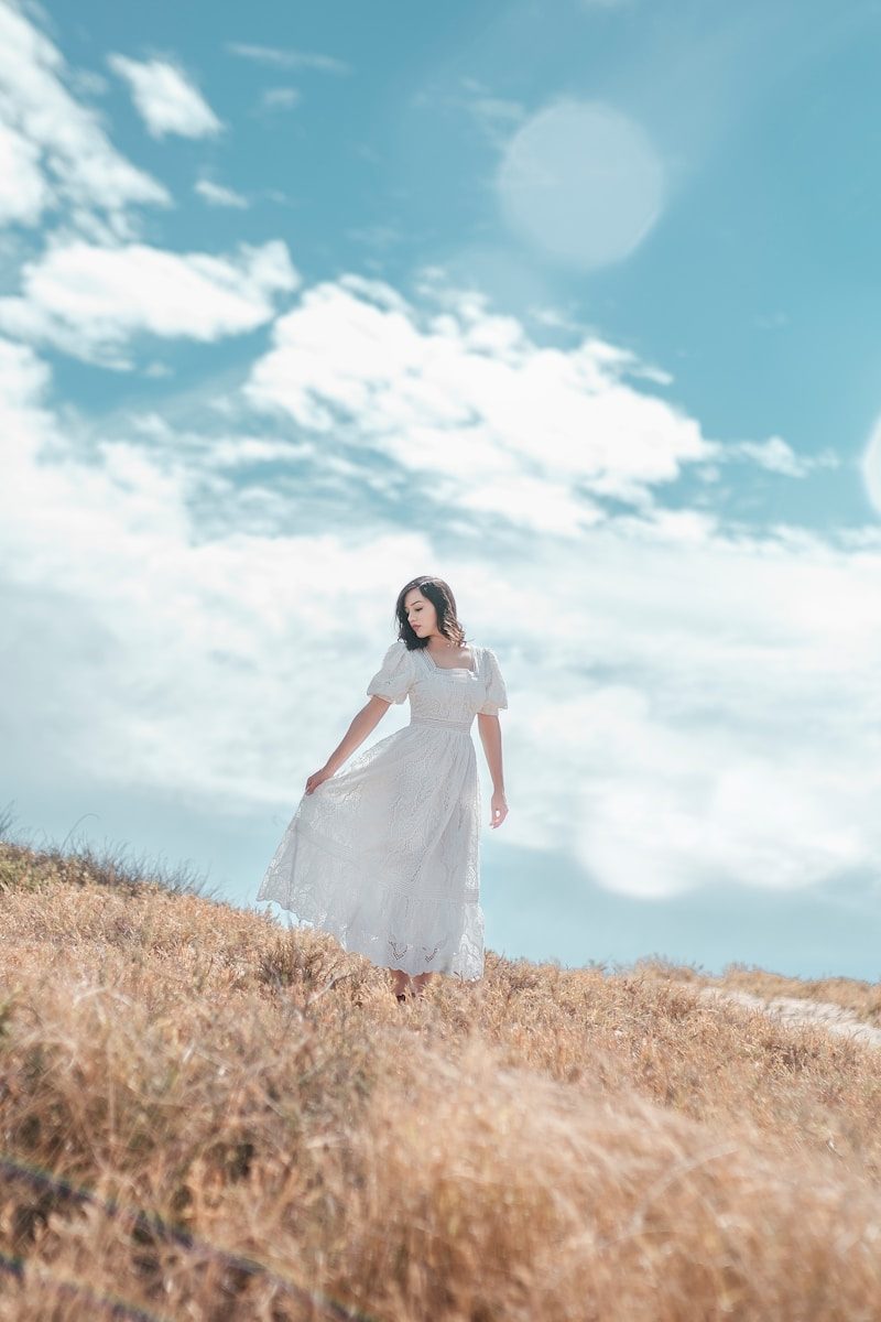 a woman in a white dress standing in a field
